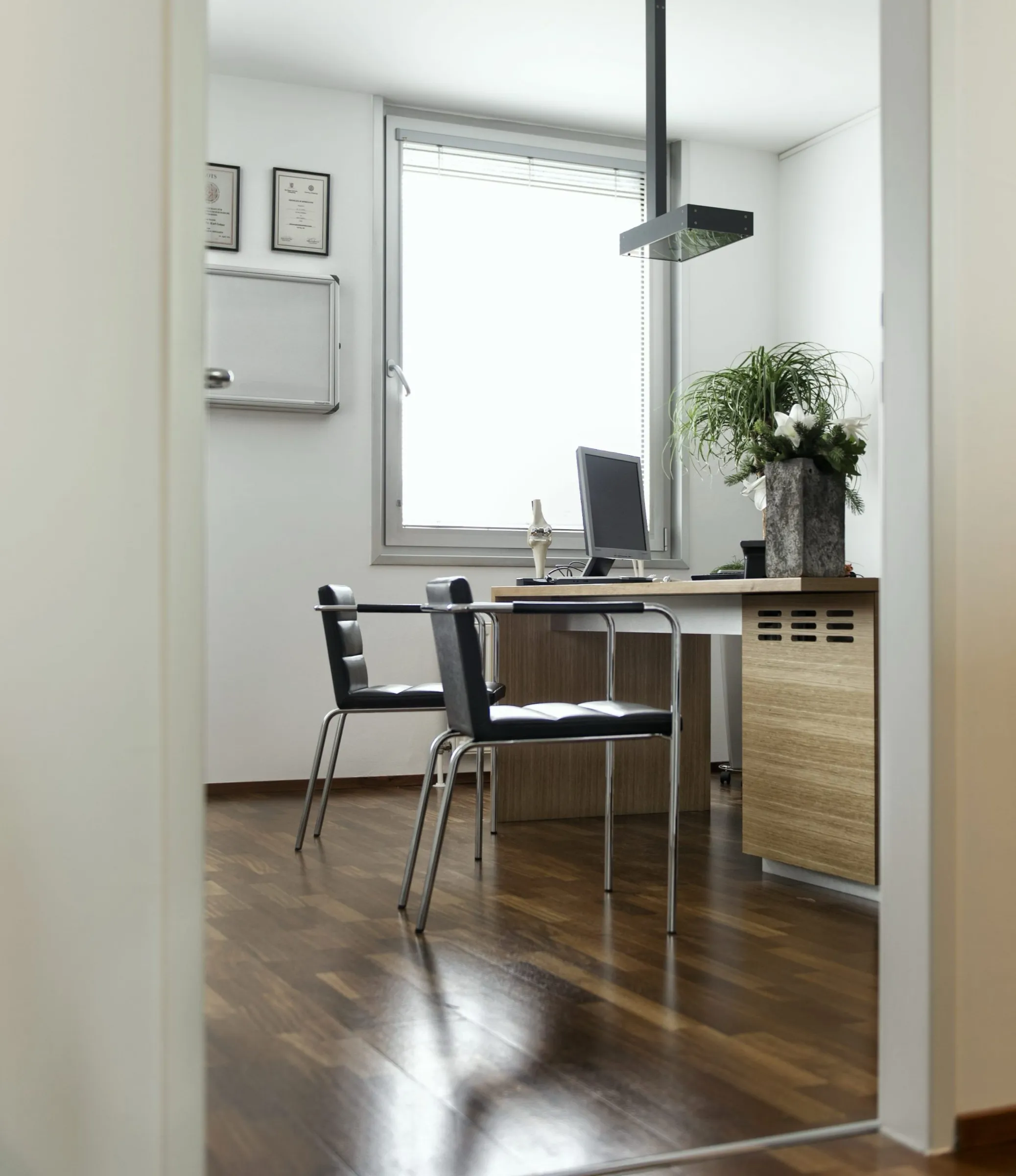 Ordinationszimmer mit Schreibtisch und Fenster